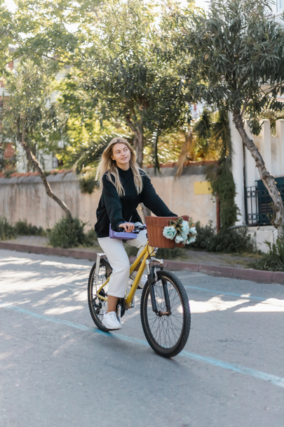 jeune femme heureuse en tenue tendance à vélo sur la rue ensoleillée en dinde - Photo, image
