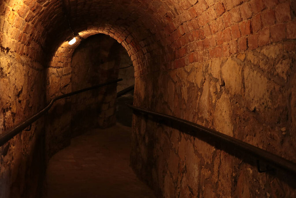 Κατεβείτε σε ένα σκοτεινό μακρύ υπόγειο, πέτρινη κατασκευή, καταφύγιο - Φωτογραφία, εικόνα