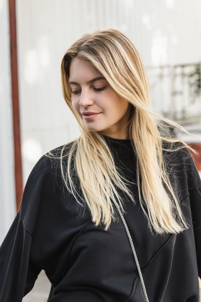 portrait of young blonde woman in black sweater on street in turkey  - Foto, Imagen