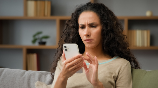 Closeup angry confused puzzled stressed nervous adult woman looking at cellphone screen at home has trouble with wifi connection feeling frustrated of receiving message or email with bad news chatting - Photo, Image
