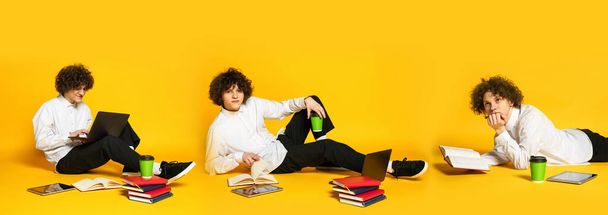 Porträt eines jungen Mannes, der auf dem Boden sitzt und isoliert vor gelbem Hintergrund Hausaufgaben macht. Collage. Bildungskonzept, Studium und Studentenleben, Prüfungen - Foto, Bild