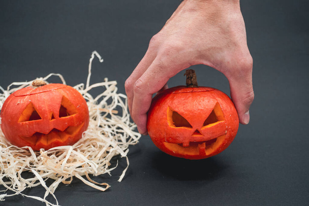 Halloween pumpkin. Halloween decoration. Man holding in hand a scary face pumpkin. Halloween pumpkin on a black background. - 写真・画像