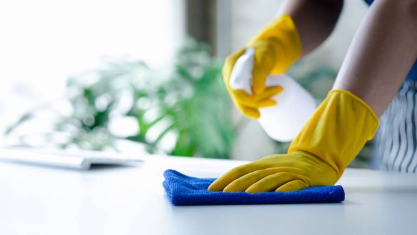 Osoba sprzątająca pokój, personel sprzątający używa tkaniny i środka dezynfekującego do wycierania stołów w biurze firmy. Sprzątacze. Utrzymanie czystości w organizacji. - Zdjęcie, obraz