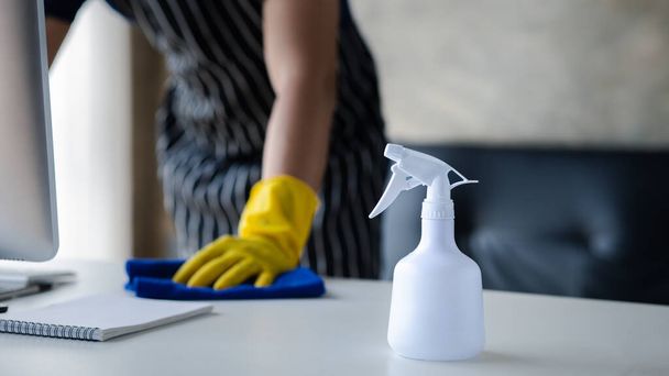 Person cleaning the room, the cleaner is wiping the desk in the company office. Cleaning staff. Concept of cleanliness in the organization. - Foto, imagen