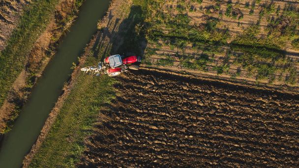 Luftaufnahme mit der Drohne eines Traktors, der das Land in der Landschaft pflügt. - Foto, Bild