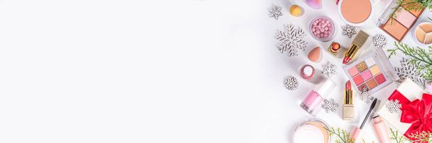 Invierno y Navidad decorativo maquillaje cosméticos, copos de nieve artificiales, ramas de árboles de Navidad, cajas de regalo, accesorios de belleza. Navidad y Año Nuevo venta de cosméticos de invierno plano yacía sobre fondo blanco - Foto, imagen