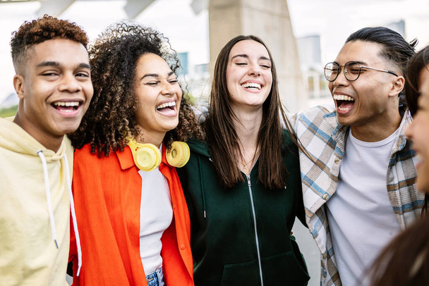 Multiracial group of young friends laughing together outdoors - United millennial diverse people hugging each other while having fun on vacation trip - Friendship and international community concept - Photo, Image