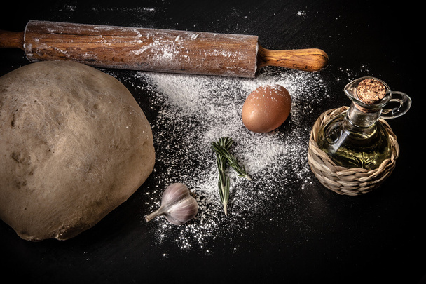 dough on a board with flour. olive oil, eggs, rolling pin, garli - 写真・画像