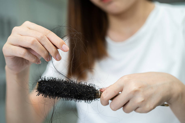 Asian woman have problem with long hair loss attach to comb brush. - Photo, image