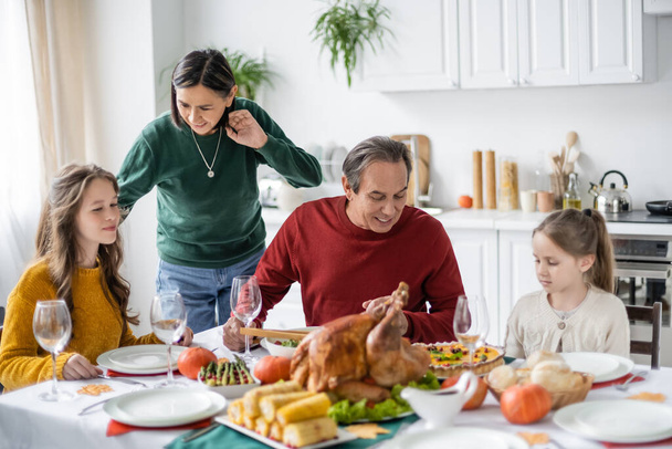 Smiling multiethnic grandparents talking to kids near thanksgiving dinner at home  - Photo, Image