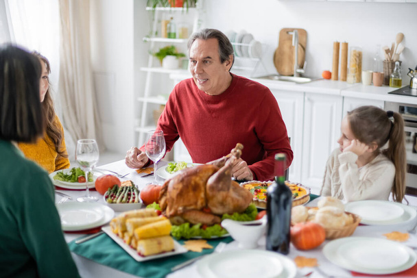 Oudere grootouders in gesprek met familie in de buurt wazig Thanksgiving diner thuis  - Foto, afbeelding
