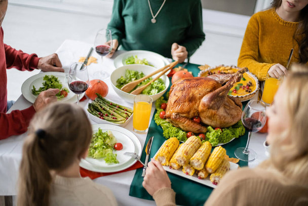 Overhead view of tasty dinner near family celebrating thanksgiving at home  - Foto, imagen