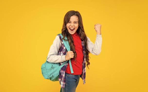 successful kid has long curly hair carry school backpack on yellow background, knowledge. - Фото, изображение