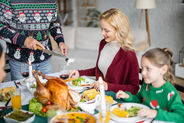 nainen hymyilee lähellä isä leikkaa lihaa kiitospäivän aikana illallinen perheen kanssa - Valokuva, kuva