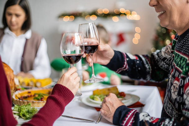 smiling man clinking wine glasses with daughter during festive thanksgiving dinner - Fotó, kép