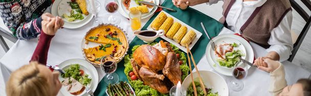 top view of family holding hands and praying near delicious thanksgiving dinner, banner - Zdjęcie, obraz