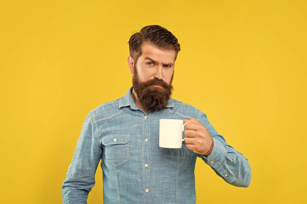 Serious caucasian man holding mug yellow background, tea break. - Fotografie, Obrázek