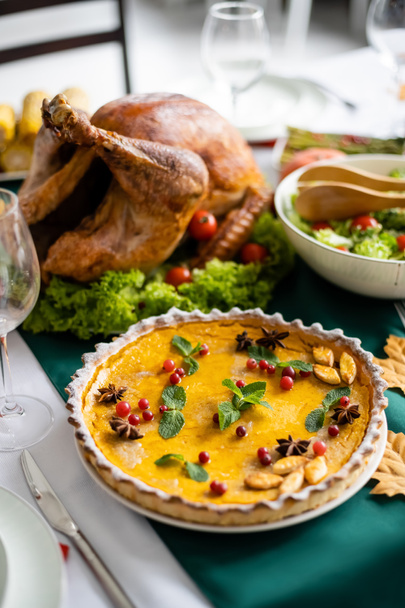 традиційний гарбузовий пиріг з журавлиною біля смаженої індички та свіжим овочевим салатом, який подається на вечерю подяки
 - Фото, зображення