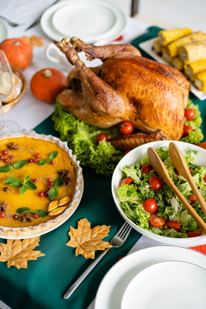 high angle view of roasted turkey near fresh vegetable salad and pumpkin pie with cranberries - Photo, Image