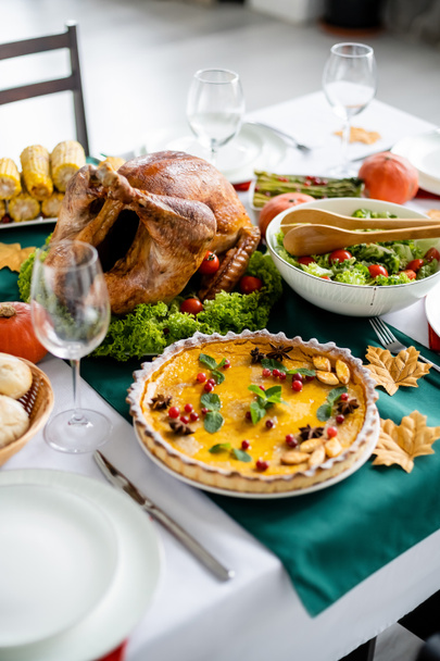 delicious roasted turkey near traditional pumpkin pie with cranberries and mint leaves served for thanksgiving dinner - Photo, Image