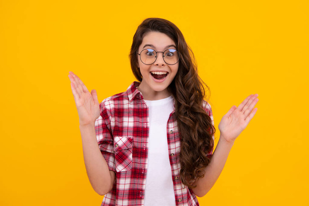 Child with positive expression, joyful and exciting over yellow background with empty space. Happy teenager girl rejoices success. Amazed teenager. Excited teen girl - Photo, Image