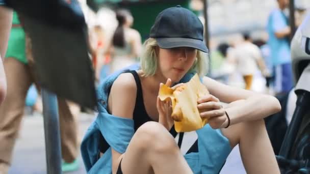 Hungry teenage girl eating pizza calzone on the street. - Footage, Video