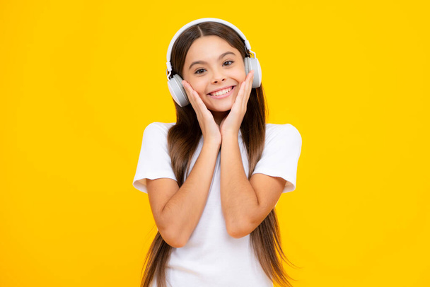 Child music concept. Teenager child girl dances in rhythm of melody, listens song in headphones. Child listening to music through earphones. Happy teenager portrait. Smiling girl - Photo, Image