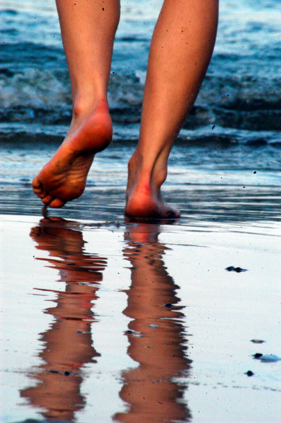 human walking barefoot in the water at a sandy beach - Photo, Image