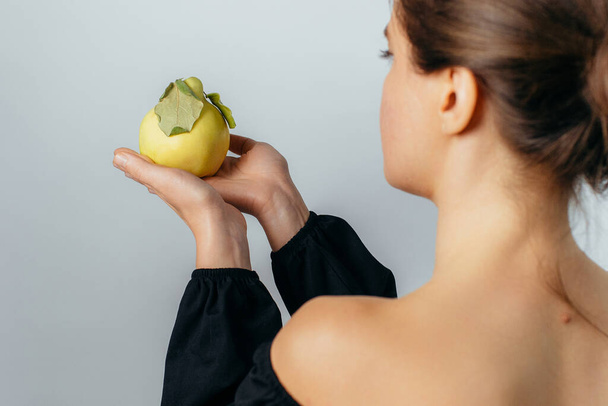 молода жінка тримає стиглий фрукт айви в долоні. Високоякісна фотографія
 - Фото, зображення