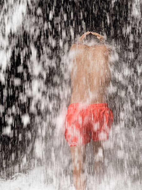 Hombre parado bajo una cascada - Foto, imagen