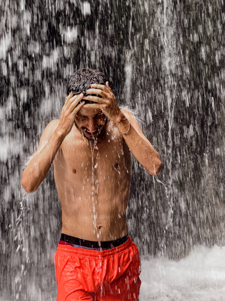 Чоловік стоїть під водоспадом
 - Фото, зображення