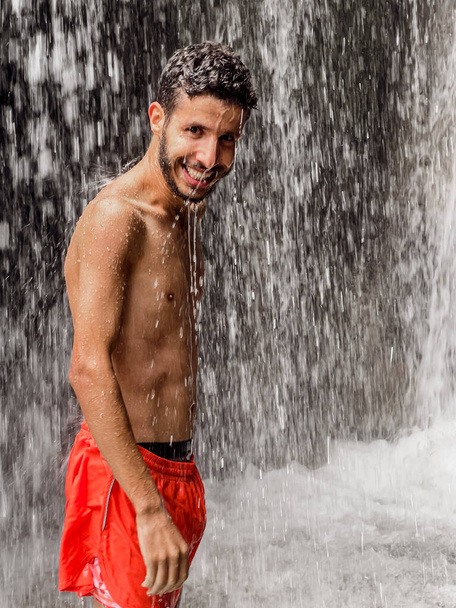 Mann steht unter einem Wasserfall - Foto, Bild