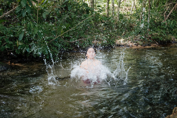 Enfant jouant dans l'eau et s'amusant entouré par la nature et de nombreuses couleurs - Photo, image