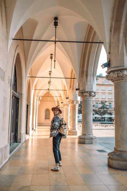 Περπάτημα νεαρή ενήλικη καυκάσια γυναίκα ταξιδιωτικό σακίδιο. Άνθρωποι που ταξιδεύουν στην πόλη lifestyle παλιά πόλη αγορά δρόμο Κρακοβία, Πολωνία.  - Φωτογραφία, εικόνα