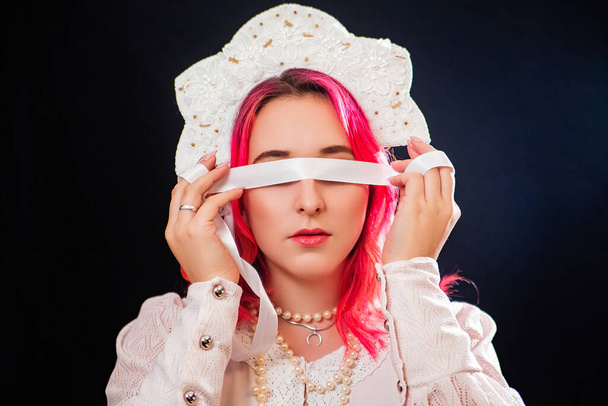 Close-up portrait of a woman with pink hair in a white dress with a kokoshnik on her head posing isolated on a black background. - Fotoğraf, Görsel