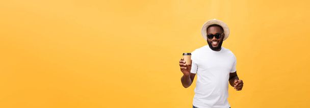 Elegante joven afroamericano que sostiene la taza de café para llevar aislado sobre fondo amarillo
 - Foto, Imagen
