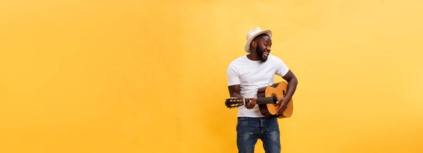 Ολόσωμο φωτογραφία συγκινημένο άνθρωπο καλλιτεχνική παίζοντας την κιθάρα του. Απομονωμένα σε κίτρινο φόντο - Φωτογραφία, εικόνα