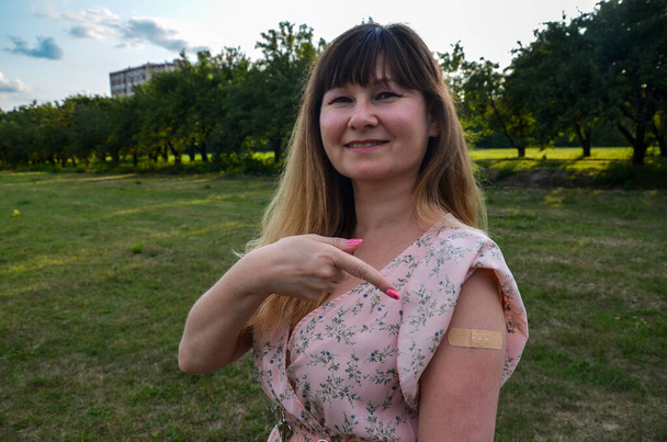 Vakcinovaná žena s náplastí po aplikaci injekce vakcíny Covid-19. Koronavirová vakcinační kampaň - Fotografie, Obrázek