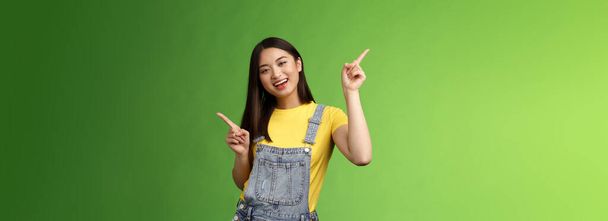 Przyjazny stylowy przystojny optymistyczny nastolatek azjatycki brunetka, taniec radośnie pokazując kilka wyborów, zakupy online łatwe zbieranie produktów, wskazując bokiem w lewo w prawo, uśmiechnięty entuzjastyczny. - Zdjęcie, obraz