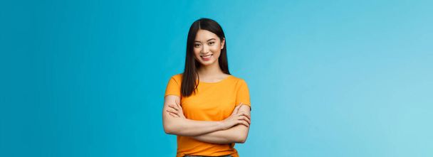 Confident assertive good-looking asian girl with dark short hairstyle cross arms chest self-assured, ready help give advice friendly smiling camera, stand blue background upbeat motivated. - 写真・画像