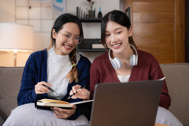 Dva asijské studenti učení společně online s notebookem a lektorem společně doma. - Fotografie, Obrázek