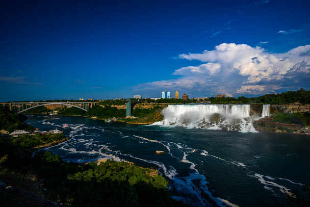 Canadese zijaanzicht van Niagara Falls, American Falls, Horseshoe Falls, Niagara River, toeristische attracties, casino 's, vuurwerk en boottochten bij zonsondergang; Niagara Falls, Ontario, Canada - Foto, afbeelding