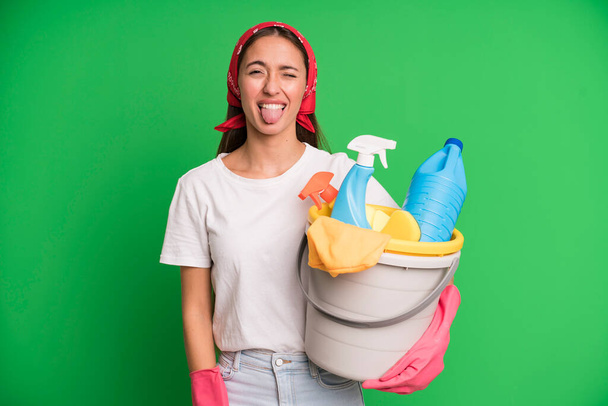 young pretty woman with cheerful and rebellious attitude, joking and sticking tongue out. housekeeper and cleaner concept - Photo, Image