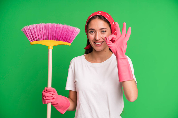 young pretty woman feeling happy, showing approval with okay gesture. housekeeper and cleaning concept - Foto, afbeelding