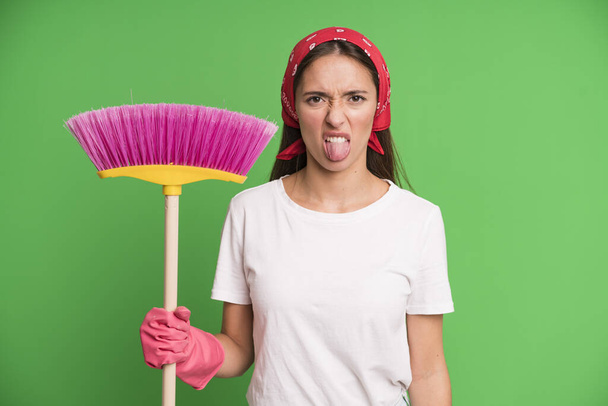young pretty woman feeling disgusted and irritated and tongue out. housekeeper and cleaning concept - Фото, изображение