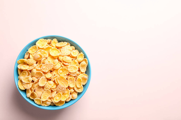 Bowl of tasty crispy corn flakes on light background, top view. Space for text - Foto, imagen