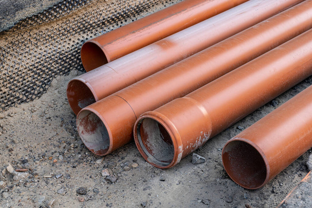 Stack of brown pvc pipes. Close up of orange plastic pipes on construction. Industrial background - Photo, Image