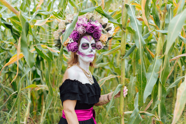 Πορτραίτο μιας γυναίκας φτιαγμένης ως Κατρίνα σε χωράφι με καλαμπόκι. Μεξικανή που αντιπροσωπεύει τον χαρακτήρα της ημέρας των νεκρών.. - Φωτογραφία, εικόνα