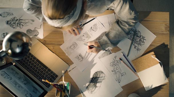 Fiatal nő dolgozik egy storyboard egy design stúdióban. Egy laptop és egy helyhez kötött üveg az asztalon. Nő rajz vázlatok, mint egy útiterv a videó. - Fotó, kép