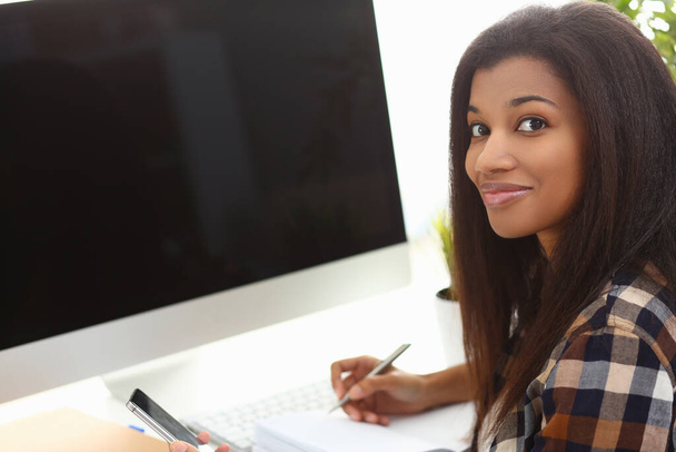 Black business woman holding phone making notes in modern office. Mobile apps fucking business concept - 写真・画像